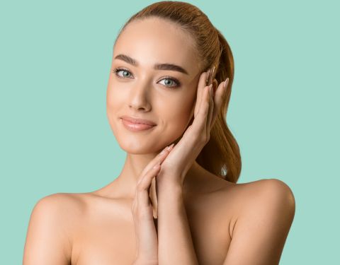 A stunning lady touches her face, promoting CynoGlow, an RF Microneedling procedure provided at Gulf Breeze, Florida's Living Waters Regenerative Medicine Center.